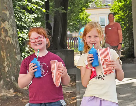 Zwei Schülerinnen trinken und essen auf dem Schulfest