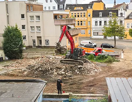 Abriss-Bagger vor dem abgerissenen Gebäude
