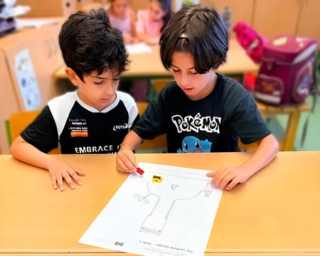 Kinder am Schultisch mit Arbeitsblatt