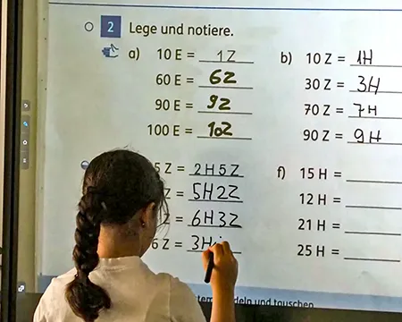 Kind löst Mathematikaufgaben an der Tafel