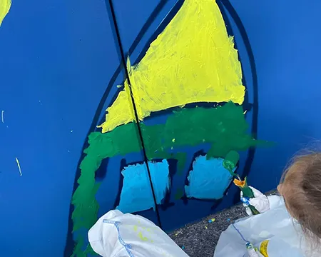 Ein Schulkind bemalt eine Wand